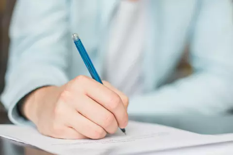 Detailaufnahme einer Person, die mit einem Stift schreibt