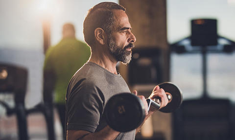 Mann im Fitnessstudio trainiert mit Gewichten