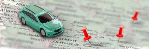 Spielzeugauto auf einer Landkarte mit roten Stecknadeln