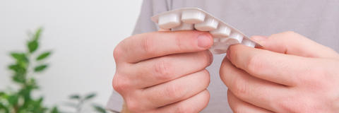 Mann hält Blister mit Tabletten in den Händen
