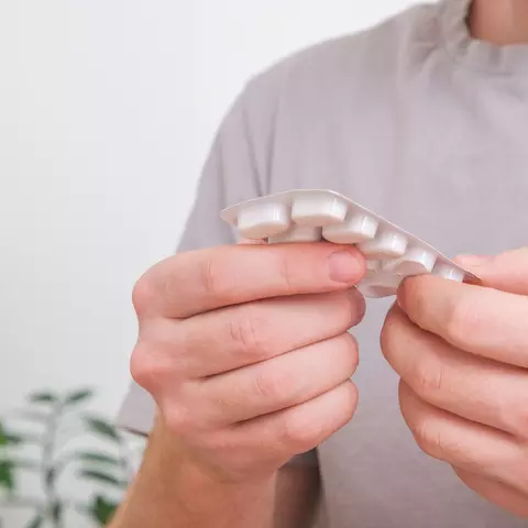 Mann hält Blister mit Tabletten in den Händen