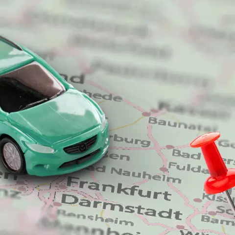 Spielzeugauto auf einer Landkarte mit roten Stecknadeln